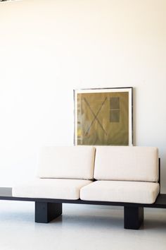 a white couch sitting in front of a painting on the wall