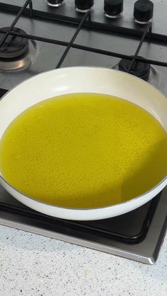 a white bowl filled with green liquid on top of a gas stove burner next to an oven