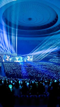 a large group of people standing in front of a stage with bright lights on it