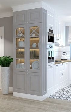 a kitchen with white cabinets and an oven in the corner, next to a potted plant