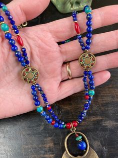 Featuring stones that are associated with wisdom, insight, spirituality, and communication, this is made with gorgeous deep royal blue to navy blue grade A Lapis in various shapes and sizes, which contrast strikingly with green semi precious turquoise, rich red Czech glass and white-heart beads, and brass spacers. The two strands gather at Tibetan brass 15mm coin beads inlaid with red coral and turquoise howlite as well as other brass beads. A 53x37mm plated antique gold large tribal style medal Blue Turquoise Necklace For Healing, Round Blue Turquoise Necklace For Healing, Blue Turquoise Gemstone Beads Necklace For Spiritual Style, Spiritual Blue Turquoise Necklace With Gemstone Beads, Spiritual Turquoise Pendant Necklace For Festival, Spiritual Round Turquoise Necklace, Spiritual Multicolor Turquoise Necklace For Festivals, Blue Turquoise Necklace For Festivals Gift, Blue Turquoise Necklace For Festivals And Gifts