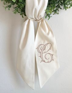 an embroidered monogram on the side of a white bow tie hanging from a wall