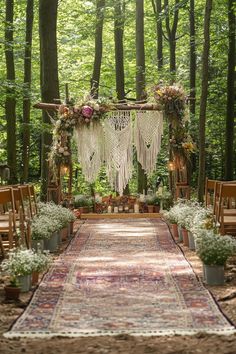 an outdoor wedding ceremony setup in the woods with flowers and greenery on the aisle