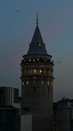 a tall tower with a clock on it's side at night, lit up by lights