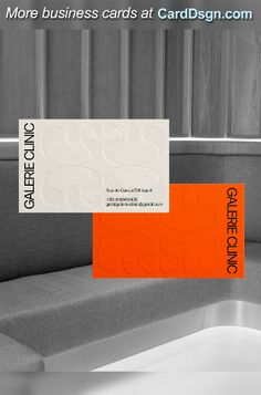 an orange and white business card sitting on top of a gray couch