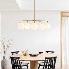 a dining room table with four chairs and a vase on the table next to it