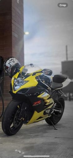 a yellow and black motorcycle parked next to a brick building with a gas pump on it's side