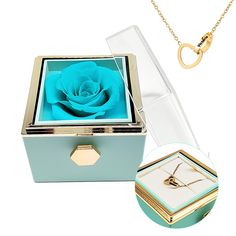 a jewelry box with a blue rose in it and a gold ring hanging from the lid