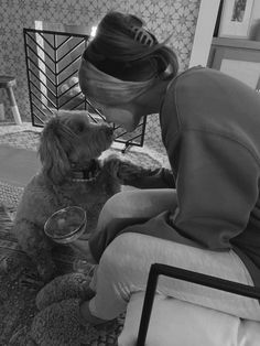 a woman sitting on the floor with her dog and drinking from a glass in front of her