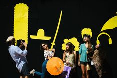 a group of people standing next to each other near a yellow and black wall with letters on it