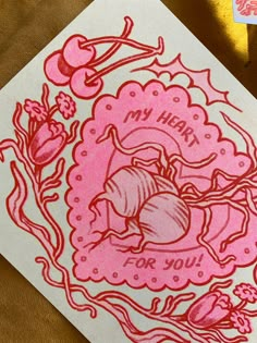 a pink and white card with an image of a heart surrounded by flowers on it