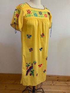 "Beautiful, vibrant yellow cotton dress with bright floral, butterfly, and peacock hand embroidered cross stitch design. So sweet! I'm not sure what to call the gathered decorative stitching that holds each piece to the next but it's beautiful.  Laid flat it measures- Shoulder 14.5\" Pit to pit 15\" Waist 20.5\" Length 40\" Fits like a XS/S Hand wash cold, dry flat Please ask any questions prior to purchase and see all photos, all sales are final, thank you!" Yellow Summer Embroidered Dress, Yellow Embroidered Summer Dress, Yellow Folk Dress For Spring, Fiesta Embroidered Cotton Dress With Multicolor Embroidery, Traditional Yellow Embroidered Dress For Spring, Yellow Cotton Dress With Floral Embroidery, Multicolor Embroidered Cotton Dress For Fiesta, Traditional Yellow Cotton Dress, Yellow Cotton Festival Dress