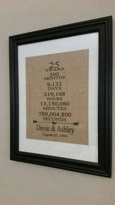 a cross stitch pattern hanging on the wall next to a black framed frame that says 25 years