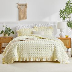 a bed with white sheets and pillows in a room next to a plant on the wall