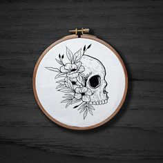 a black and white drawing of a skull with flowers on it's head in a hoop