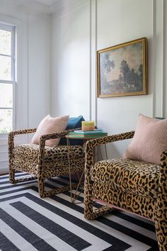 two leopard print chairs sitting next to each other on top of a black and white rug