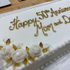 a 50th anniversary cake with white flowers and gold lettering