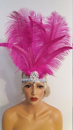 a mannequin wearing a pink feather headpiece on top of a white wall