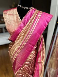 Indulge in ethereal elegance with our exquisite Kora Tissue Silk Saree, featuring a luxurious Katan Silk border adorned with shimmering gold zari. This masterpiece combines the delicate transparency of Kora tissue with the rich texture of Katan silk, creating a captivating contrast. The saree's ethereal beauty is further enhanced by the intricate gold zari work on the border, adding a touch of opulence. Perfect for weddings, cocktail parties, or any special occasion where you desire to make a lasting impression, this saree is a must-have for the discerning woman. Fabric: Kora by Tissue Silk Saree with Katan Silk Border Color: Rose Gold Embellishments: Gold Zari Occasion: Weddings, Parties, Festive Photos don't do justice .. this saree is just... glamorous Comes with fall/ Pico / tassels an Gold Tussar Silk Pre-draped Saree With Pallu, Gold Tussar Silk Pre-draped Saree With Zari Weaving, Festive Gold Pre-draped Saree With Zari Weaving, Elegant Slub Silk Blouse Piece, Festive Fusion Silk Pre-draped Saree, Elegant Gold Pre-draped Saree For Festivals, Gold Handloom Pre-draped Saree For Wedding, Transitional Gold Chanderi Pre-draped Saree, Elegant Slub Silk Pre-draped Saree With Zari Work