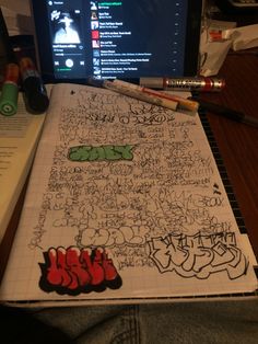 a laptop computer sitting on top of a desk covered in writing and doodled graffiti