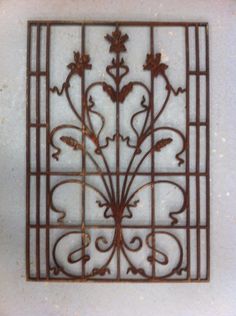 a square metal grate with flowers and vines on it's sides, hanging from the wall