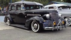 an old black car parked in a parking lot