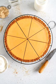 a pie sitting on top of a white table next to bowls and utensils