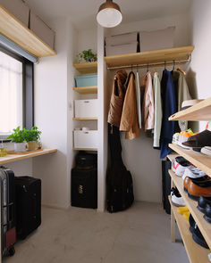 the closet is full of clothes and suitcases, including one that has a coat rack