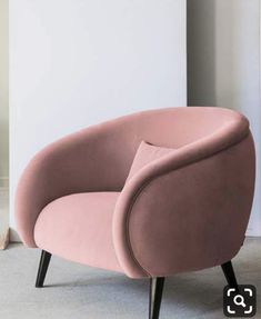 a pink chair sitting on top of a carpeted floor next to a white wall