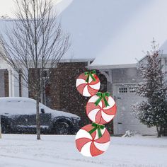 two candy canes hanging from a pole in front of a house on a snowy day