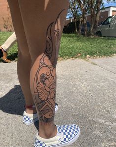 a person with tattoos on their legs standing in the street