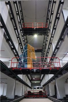 the inside of an industrial building with several vehicles parked in it and some lights on