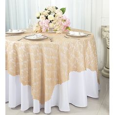 the table is set with white and gold plates, silverware and flowers on it