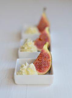 figurines in small white dishes with whipped cream and fruit toppings on them