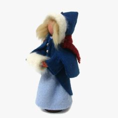 a small doll with a blue coat and red scarf on it's head, standing in front of a white background