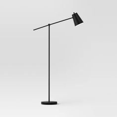 a black floor lamp on a white background with the light turned on and one arm down