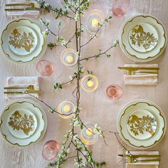 the table is set with plates, candles and napkins for an elegant dinner party