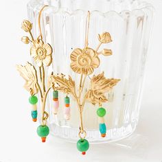 These golden brass earrings are sure to stun, with intricate detailing and three cascading bead strings hanging from the center and leaves. Made with Fair Trade Turquoise, blue, green, cream, pink, and coral beads, they are a stylish addition to any outfit! • 2" long 24K • Gold-plated hammered French ear wires Designed by Tamar and handmade by a team of wonderful women in their Burlington, Vermont studio. They donate monthly to various causes that help women and children in need around the world Delicate Gold Beaded Earrings, Elegant Gold Earrings With Colorful Beads, Gold Beaded Earrings With Colorful Beads, Gold Flower Earrings With Dangling Beads As Gift, Gold Chandelier Earrings With Colorful Beads As Gift, Gold Dangle Earrings With Colorful Beads, Gold Drop Earrings With Colorful Beads, Gold Beaded Flower Earrings With Ear Wire, Bohemian Gold Flower Earrings With Round Beads