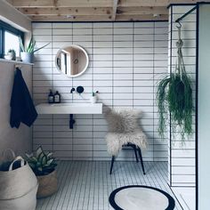 a white tiled bathroom with plants on the wall and a chair in the corner next to the sink