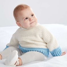 a baby sitting on a bed wearing a sweater and leggings