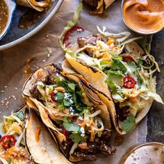 three tacos on a table with sauces and condiments