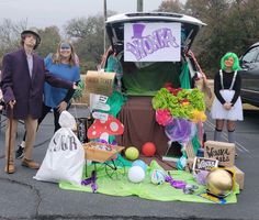 three people standing in front of a car with decorations on the hood and bags full of stuff