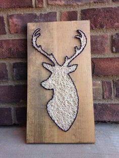 a wooden sign with a deer head on it's side and string work in the middle