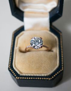 an engagement ring in a velvet box with gold trimmings and a diamond center