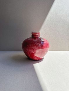 a red vase sitting on top of a white table