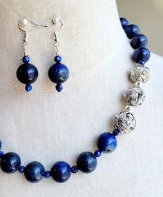 Make a statement in this one-of-a-kind lapis lazuli and silver beaded necklace and earrings set. Polished 14mm round Lapis Lazuli stone balls are strung with matching, faceted, lapis stone crystals and accented with shiny silver-plated beads all strung on wire.   The necklace is finished with stainless-steel chain and a silver-plated lobster clasp. The necklace measures 20 inches long. Matching stone beaded earrings are strung on 925 silver ear wires. Lapis Lazuli Beaded Necklaces For Jewelry Making, Round Lapis Lazuli Beaded Necklaces For Jewelry Making, Adjustable Large Beads Sterling Silver Jewelry, Adjustable Large Bead Sterling Silver Jewelry, Adjustable Large Beaded Sterling Silver Jewelry, Blue Lapis Lazuli Jewelry, Lapis Lazuli Jewelry With Natural Stones, Blue Polished Beads Jewelry, Lapis Lazuli Beaded Jewelry As A Gift