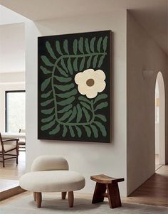 a white chair sitting in front of a painting on the wall next to a foot stool