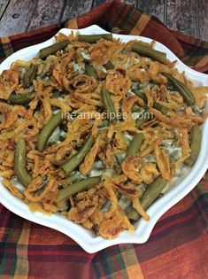 green beans and onions in a white dish on a plaid tablecloth with a wooden background