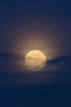 the full moon is seen through clouds in this dark night sky, with only one cloud visible