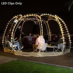 two people sitting in chairs under a tent with lights on the sides and around them